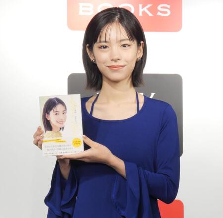 　単行本を手に笑顔を見せる當真あみ