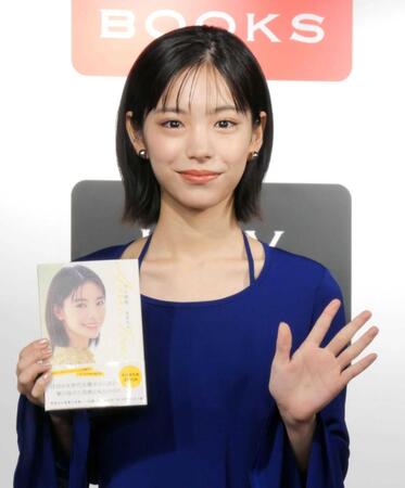 　単行本を手に笑顔を見せる當真あみ