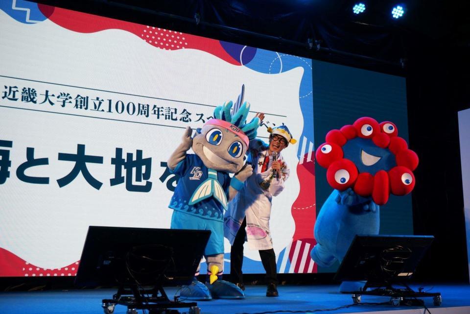 　ミャクミャク（右）と対面したさかなクン（中央）。左は近大のマスコット・ＫＩＮＤＡＩ　ＢＩＧ　ＢＬＵＥ
