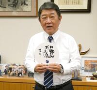 　同じ栃木県足利市出身の相田みつをさんの言葉「にんげんだもの」と書かれたうちわを持つ茂木敏充前幹事長