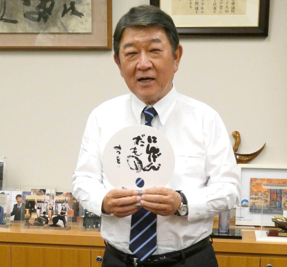 　同じ栃木県足利市出身の相田みつをさんの言葉「にんげんだもの」と書かれたうちわを持つ茂木敏充前幹事長