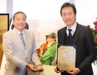 　川島なお美さんの写真の前で記念撮影をする鎧塚俊彦氏（左）と遠藤憲一