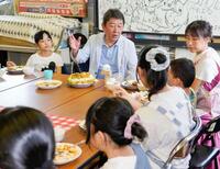 　子どもたちと食事をしながら話す自民党の茂木前幹事長（奥中央）＝21日