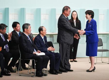 　自民党総裁選後に開かれた両院議員総会で握手する高市早苗新総裁（右端）と石破首相
