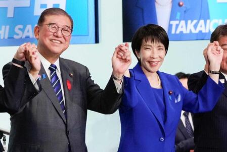 　自民党総裁選後に開かれた両院議員総会で、石破首相（左）と手を取り合う高市早苗新総裁