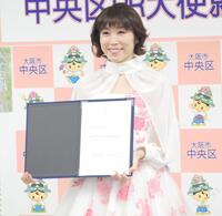 　委嘱状を手に手顔を見せる水森かおり