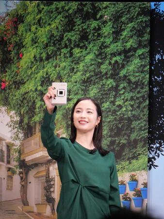 　スペインの景色を写したパネルを背景にチェキで自撮りする広瀬すず