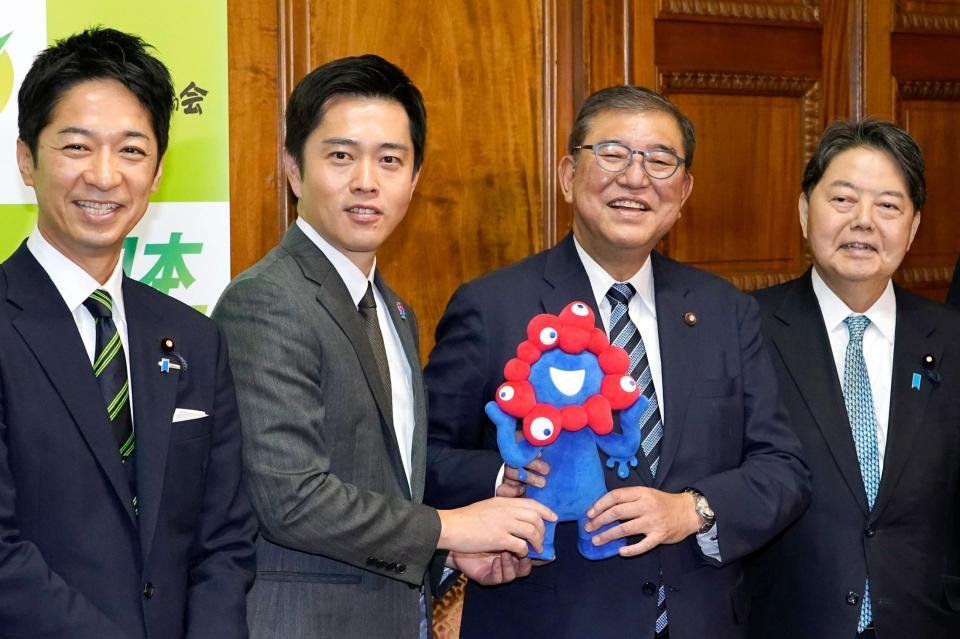 　「ミャクミャク」を手に日本維新の会の吉村洋文代表（左から２人目）らにあいさつ回りに訪れた石破茂前首相（同３人目）