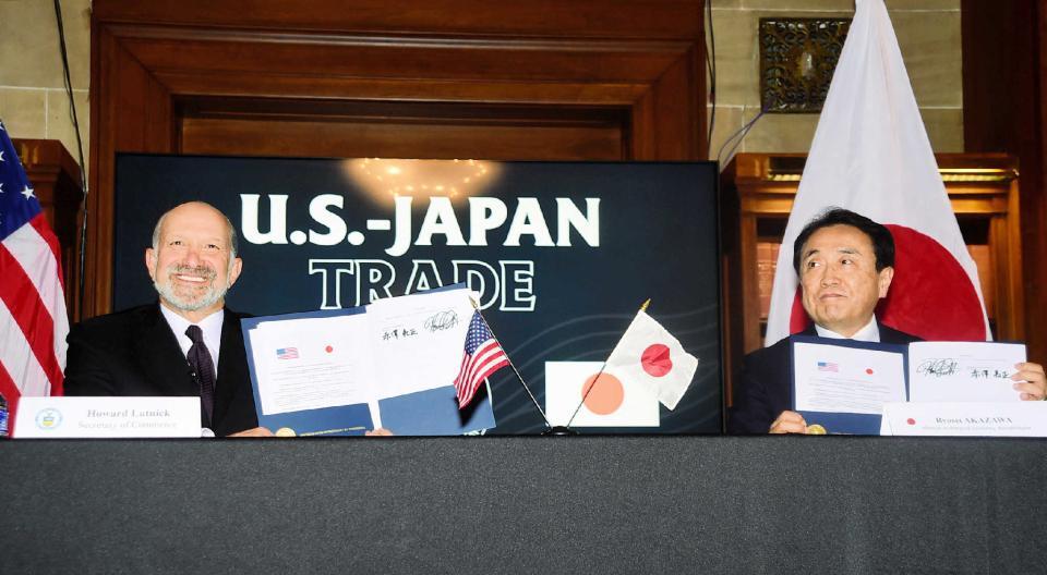 　署名した書類を見せる赤沢亮正経済再生担当相（右）とラトニック米商務長官＝９月４日（代表撮影・時事）