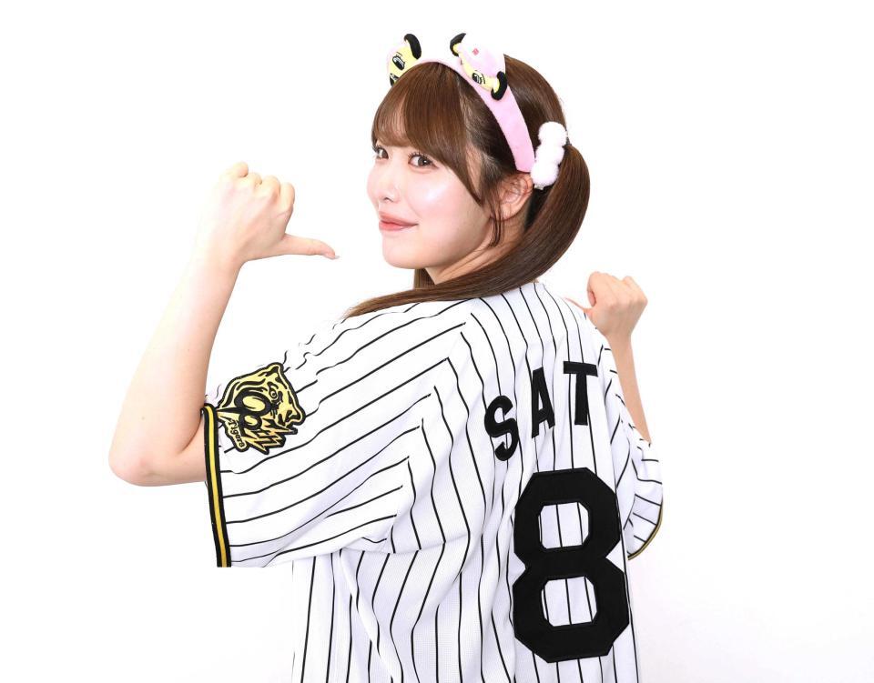 　持参した阪神・佐藤輝明選手のユニホームを着てポーズをきめる塩見きら（撮影・佐々木彰尚）