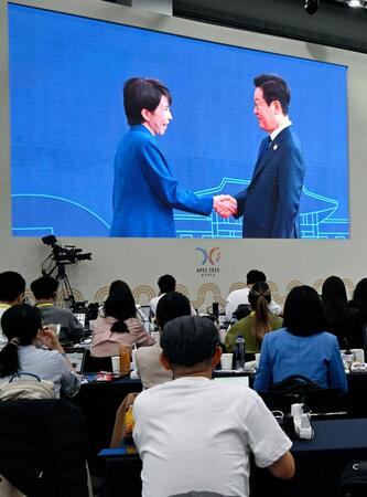 　高市首相（左）を歓迎する韓国の李在明大統領の映像を見守る記者ら＝韓国・慶州（共同）
