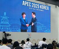 　高市首相（左）を歓迎する韓国の李在明大統領の映像を見守る記者ら＝韓国・慶州（共同）