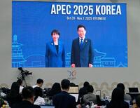 　高市首相（左）を歓迎する韓国の李在明大統領の映像を見守る記者ら＝韓国・慶州（共同）