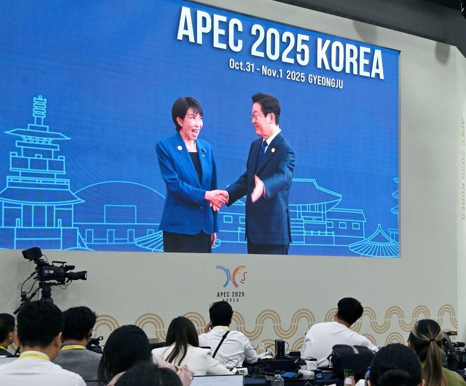 　高市首相（左）を歓迎する韓国の李在明大統領の映像を見守る記者ら＝韓国・慶州（共同）