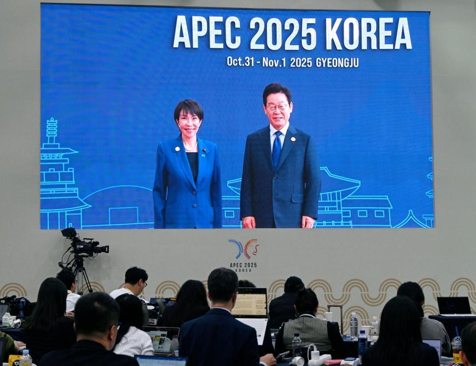 　高市首相（左）を歓迎する韓国の李在明大統領の映像を見守る記者ら＝韓国・慶州（共同）