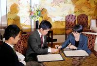 　１本の万年筆で連立政権合意書に署名する自民党の高市総裁（右）と日本維新の会の吉村代表（中央）＝１０月２０日