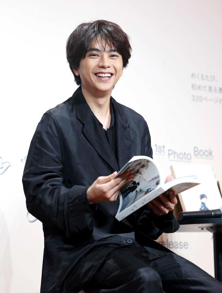 　笑顔で写真集をめくる佐藤勝利（撮影・石井剣太郎）