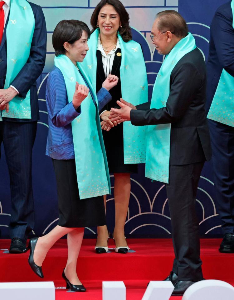 　ＡＰＥＣ首脳会議の記念撮影で、マレーシアのアンワル首相（右）と言葉を交わす高市首相（代表撮影・共同）
