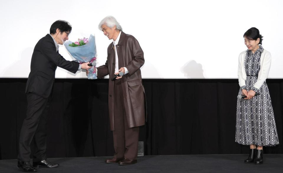 　紫綬褒章を受章した阪本順治監督（左）に花束を贈る佐藤浩市（中央）。右は吉永小百合（撮影・吉澤敬太）