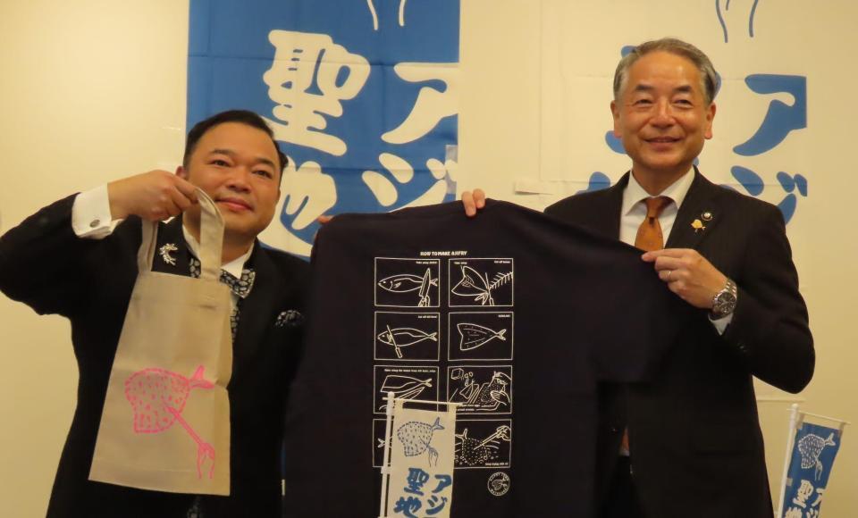 　長崎県松浦市の友田吉泰市長（右）から松浦アジフライグッズを贈呈される西寄ひがし
