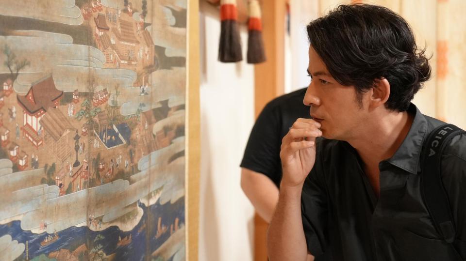 　富士山本宮浅間大社で巻物を見つめる岡田准一