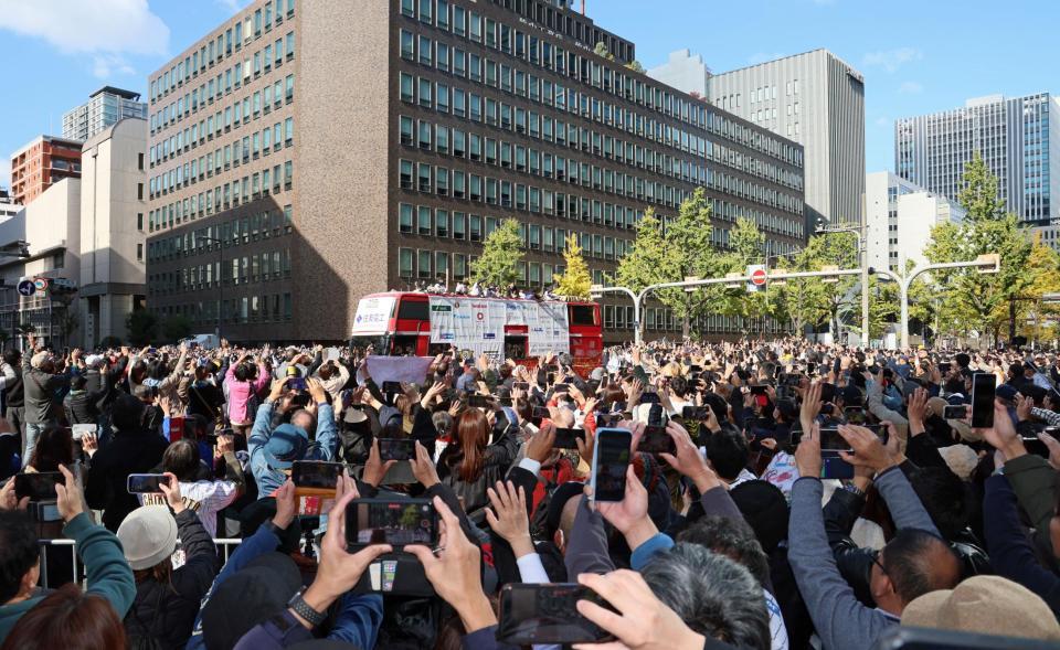 　パレードに大勢集まったファンの中を進む選手を乗せたバス（撮影・立川洋一郎）