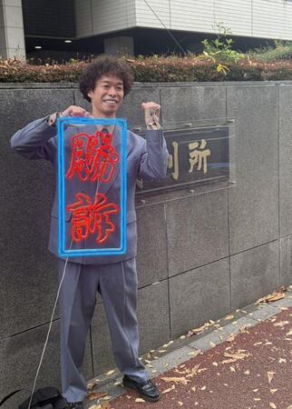 　手づくりの「勝訴」ボードを手にガッツポーズを見せた渡邊センス