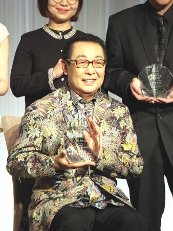 　トロフィーを手に笑顔を見せるさだまさし