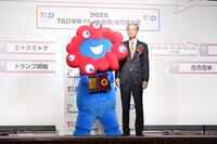 　盾を手にポーズを決める大阪・関西万博公式キャラクターのミャクミャク（左）と日本国際博覧会協会副事務総長の高科淳氏（撮影・開出牧）