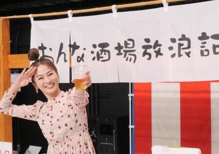 　自身が出演するＢＳ－ＴＢＳ「おんな酒場放浪記］とコラボした屋台の前でビール片手にポーズを取る倉本康子