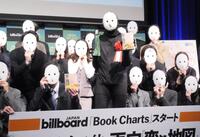 　同じ仮面のボードを手にした30人の書店店員と撮影に応じた雨穴（中央）