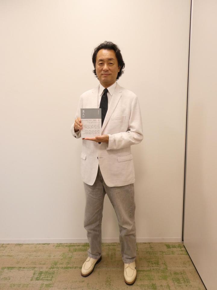 　書籍「美人」を持って撮影に応じる柘植伊佐夫氏