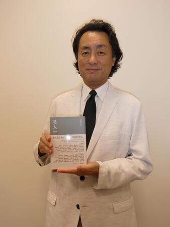 　書籍「美人」を持って撮影に応じる柘植伊佐夫氏