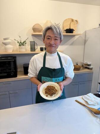 　実演調理した一皿を手に笑顔を見せる登坂淳一アナ