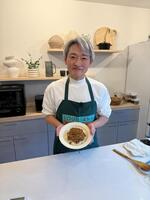 　実演調理した一皿を手に笑顔を見せる登坂淳一アナ