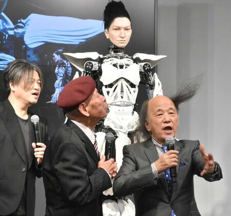 　アンドロイド・マリア（奥）の前で髪を吹き飛ばす海原はるか・かなたの海原かなた（中央）と海原はるか（右）。左は渋谷慶一郎氏