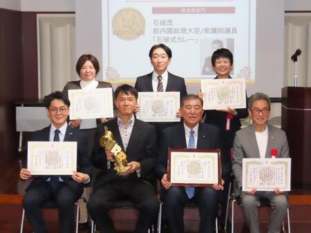 「カレー・オブ・ザ・イヤー２０２６」特別賞を受賞した石破茂前首相（下段右から２番目）と井上岳久学長（下段右から３番目）