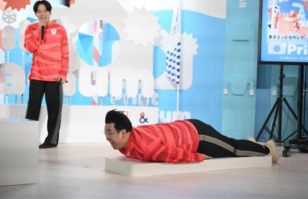 スケルトンブース体験に挑戦するレインボーのジャンボたかお。後方は池田直人（撮影・開出牧）