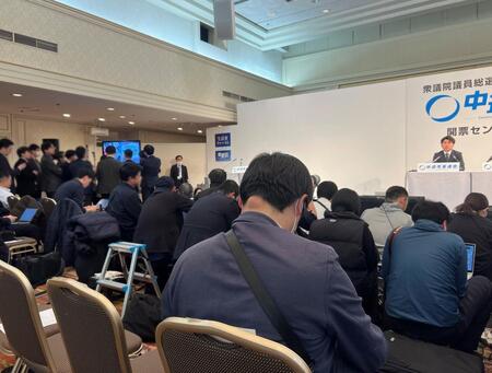 中野洋昌共同幹事長（右）をそっちのけで報道陣はテレビに群がった（写真は一部加工しています）