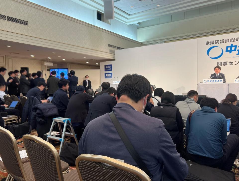 中野洋昌共同幹事長（右）をそっちのけで報道陣はテレビに群がった（写真は一部加工しています）