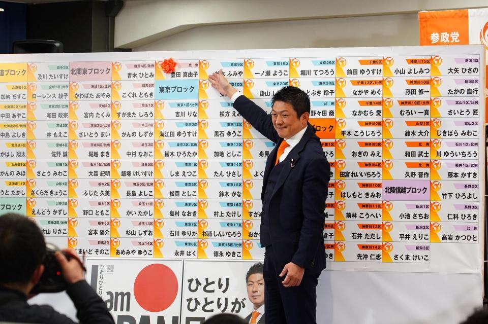 当選が確実となった豊田真由子氏の名札に花を付ける参政党・神谷宗幣代表（撮影・高石航平）