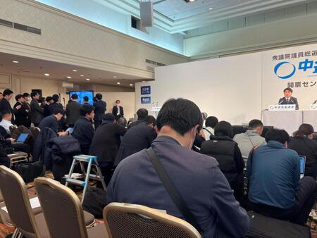 中野洋昌共同幹事長（右）をそっちのけで報道陣はテレビに群がった