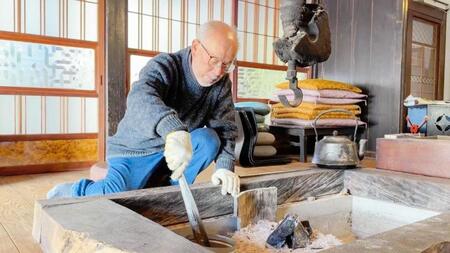 築２８８年の古民家で囲炉裏に炭をくべる大滝令嗣氏