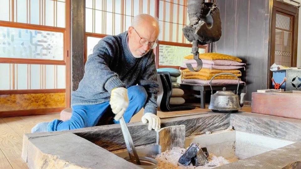築２８８年の古民家で囲炉裏に炭をくべる大滝令嗣氏