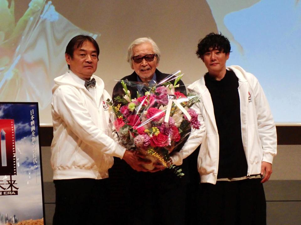 日本映画監督協会９０周年パーティーで藤井道人監督（右）から花束を贈られた山田洋次監督（中）。左は協会理事長の本木克英監督