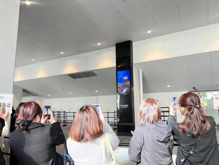 真矢さんの献花式会場外に掲出された画像を撮影するファン