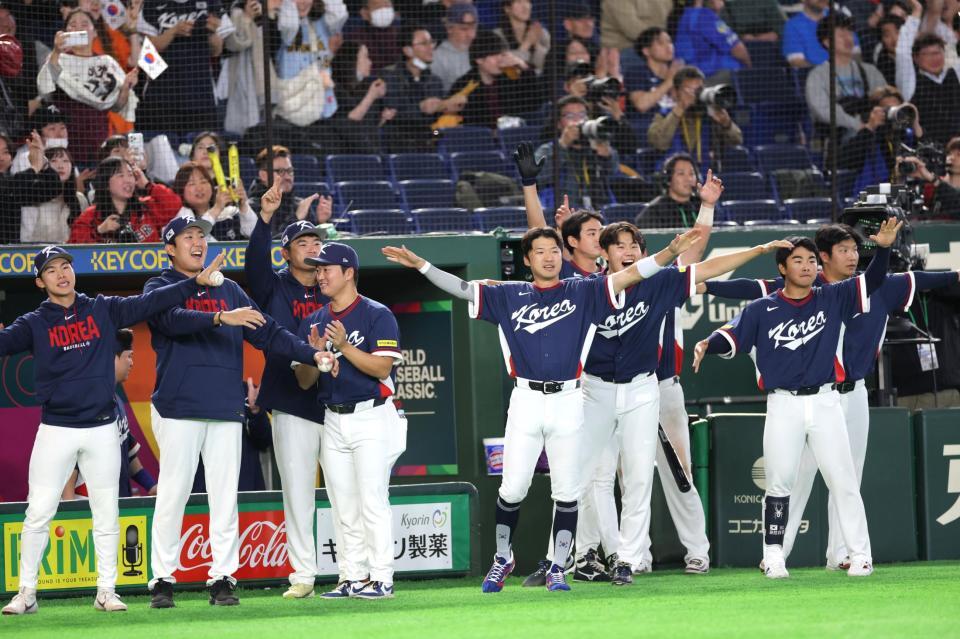 ６回、金倒永の適時打に飛行機ポーズで祝福する韓国ナイン（撮影・西岡正）