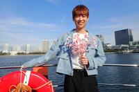 　湾岸エリアを背に笑顔の松阪ゆうき