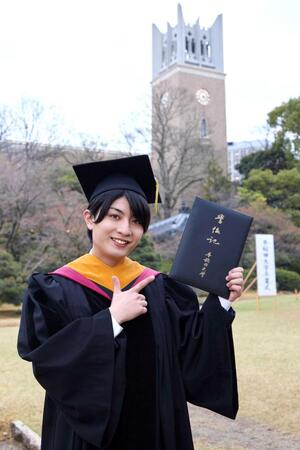 大隈講堂をバックに学位記を手にする本高克樹　