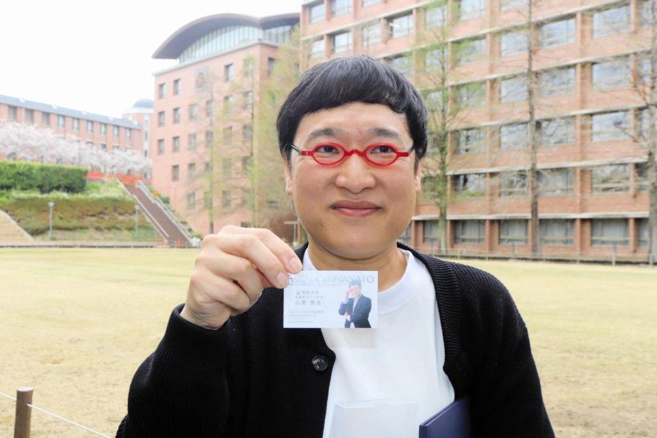 関西大卒業生アンバサダーの名刺を見せる山里亮太